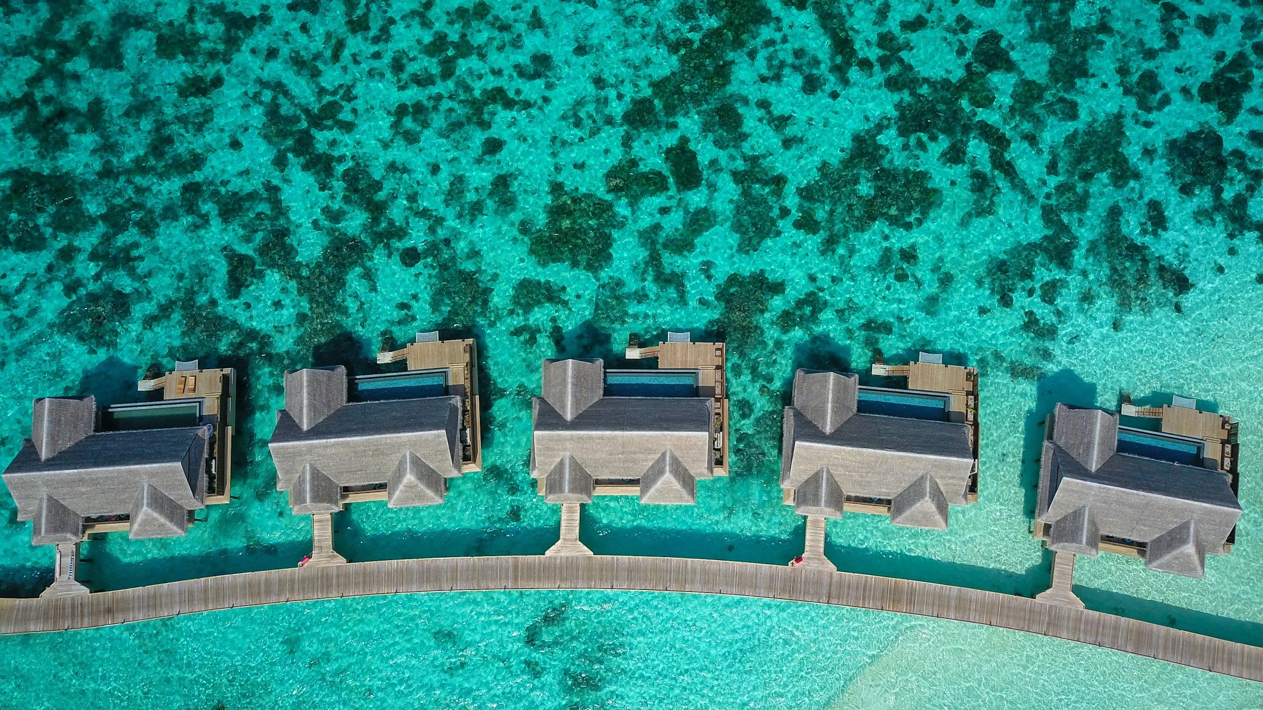 Overwater villas surrounded by vivid blue ocean in the Maldives
