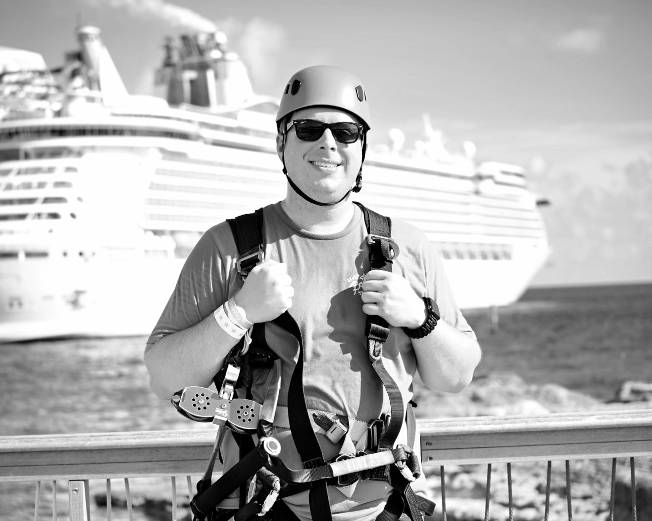 Isaiah in zip-line gear with a cruise ship behind him